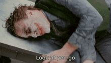a man laying on a table with the words " look at you go " below him