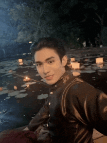 a man in a black jacket is sitting in the water with candles