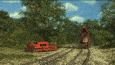 a red train is going down the tracks in a field