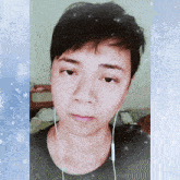 a man wearing headphones looks at the camera with snowflakes behind him