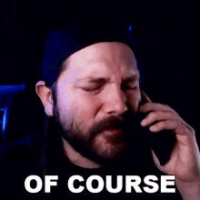 a man with a beard is crying while talking on a cell phone and the words of course are above him .