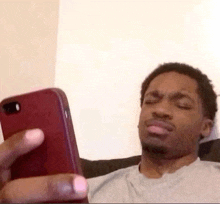 a man is laying on a couch looking at his cell phone .
