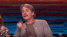 a man with a mustache is sitting in front of a screen that says nbc on it