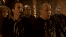 a group of men are standing next to each other in a dark room and looking at something .