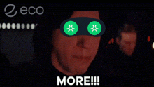 a man wearing a pair of green angry face masks with the word more written below him