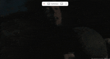 a man is holding a knife in his hand while sitting in a dark room .