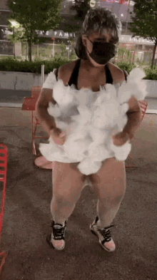 a woman wearing a mask and a costume made of cotton candy is standing on the street .