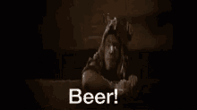 a bottle of beer is being poured into a glass in a dark room and the words beer are coming out of it .