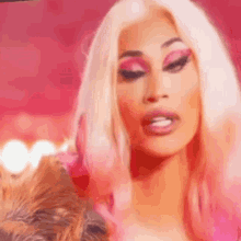 a woman with blonde hair and pink makeup is wearing a pink dress .