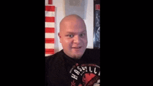 a bald man with a beard wearing a black shirt that says nashville