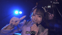a girl singing into a microphone with hulu written on the bottom right