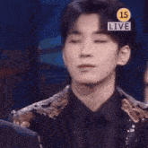 a young man in a suit and tie is standing in front of a sign that says `` live '' .