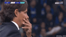 a man in a suit is watching a soccer game on bein sports live