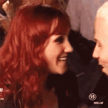 a woman with red hair is smiling and looking at a man with white hair .