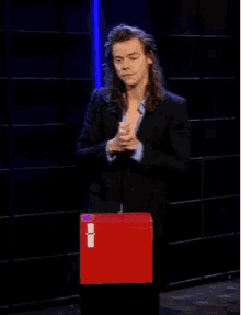 a man in a suit is standing in front of a red box with the letter i on it ..