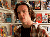 a young man in a plaid shirt is standing in front of a bookshelf with a buster book on it