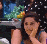 a woman is sitting at a table with her hand on her face and smiling .