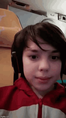 a young boy wearing headphones and a red and white jacket