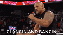 a man is holding a microphone in front of a crowd and saying clangin and bangin .