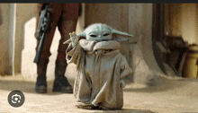 a baby yoda from star wars is standing in the sand .
