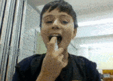 a young boy is holding something in his mouth with his fingers