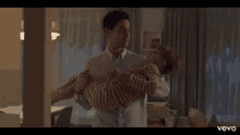 a man is holding a child in his arms and they are dancing in a living room .