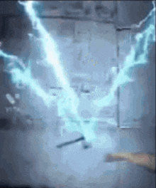 a person is holding a wand in front of a wall with lightning coming from it .
