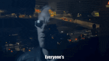 a man wearing sunglasses says " everyone 's a fucking idiot but me " in front of a city at night