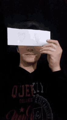 a man holding a piece of paper with hearts drawn on it in front of his face