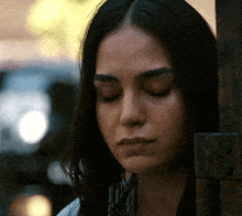 a woman with her eyes closed leans against a wall