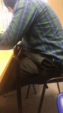 a man in a plaid shirt sits at a table