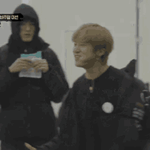 a blurry picture of a man with a backpack and a man in a hood holding a book .