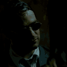 a man in a suit touches a woman 's face in the dark