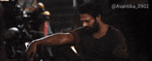 a man with a beard is sitting down with the hashtag avantika_0902 on the bottom right