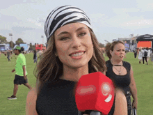 a woman wearing a zebra print head scarf is holding a red microphone with the number 6 on it