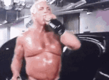 a shirtless man is drinking from a bottle .