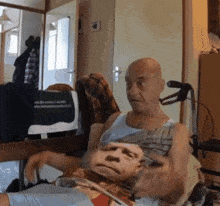 a bald man in a tank top holds a picture of a man 's face
