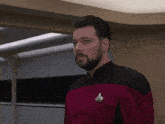 a man with a beard is wearing a red and black uniform with a star trek pin