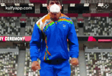 a man wearing a mask and a blue jacket is running on a stadium .