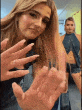 a woman with long nails is making a stop sign with her hands