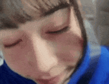 a close up of a person 's face with a blue shirt on .