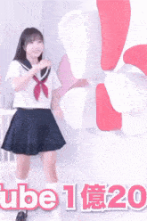 a girl in a sailor uniform is dancing in front of a windmill with the number 20 in pink