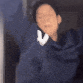 a man in a blue jacket is making a funny face with his hands in the air