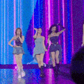 a group of women are standing on a stage in front of a purple and blue curtain