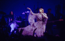 a woman in a long purple dress sings into a microphone on stage