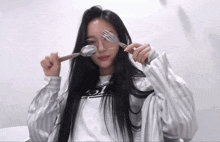 a woman holding a spoon and fork in front of her eyes