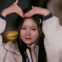 a woman is making a heart shape with her hands on her head