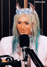 a woman with blonde hair and blue hair is sitting in front of a microphone
