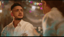 a man in a white shirt is looking at another man in a white shirt .