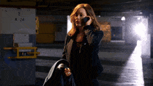 a woman talking on a cell phone in a parking garage with a sign that says k 24